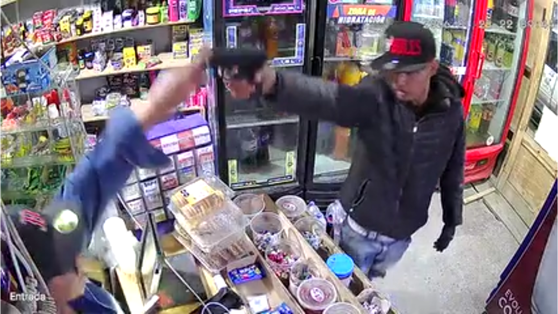 A still frame from the CCTV video showing the suspect at the counter moments before the confrontation, without visible weapons in close-up.