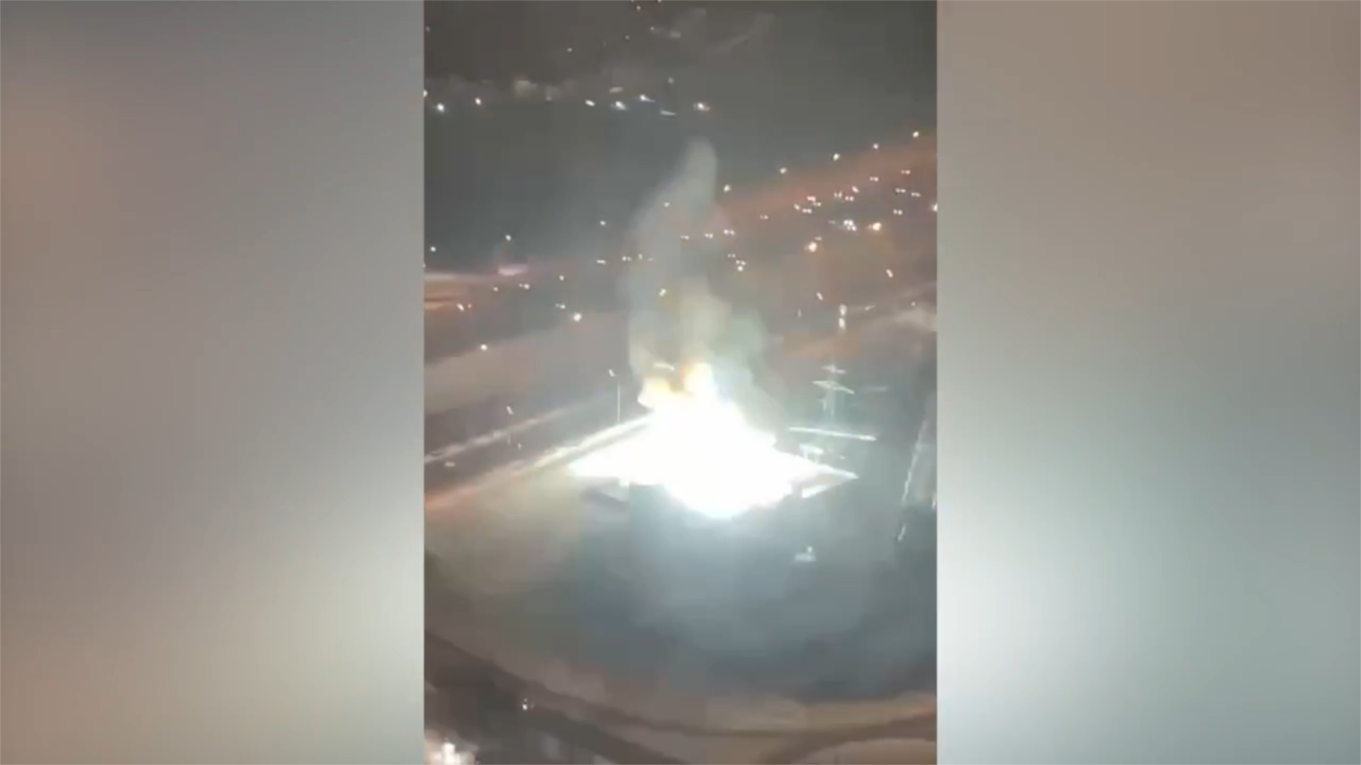 A still frame from the video showing the bright flash illuminating the substation area at night, without visible damage or people.