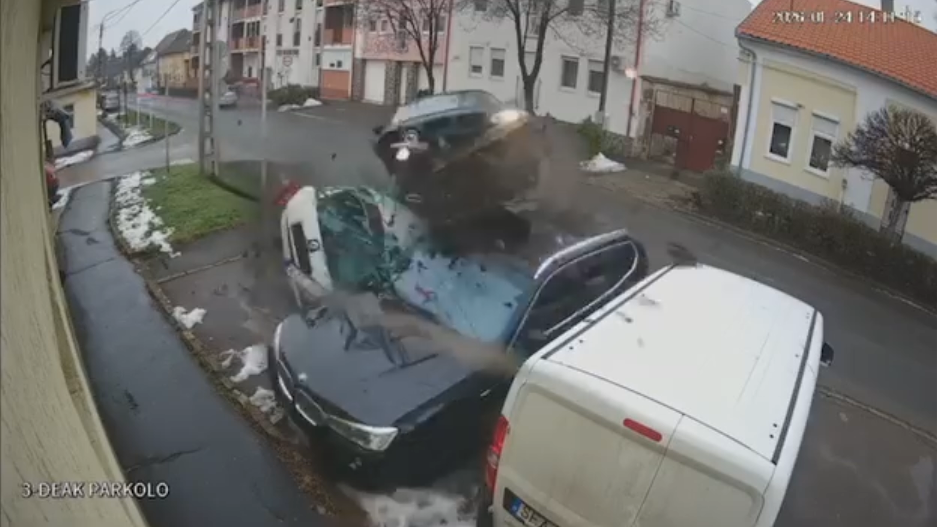 A still frame from the video showing the moment the car is airborne above parked vehicles on the street.