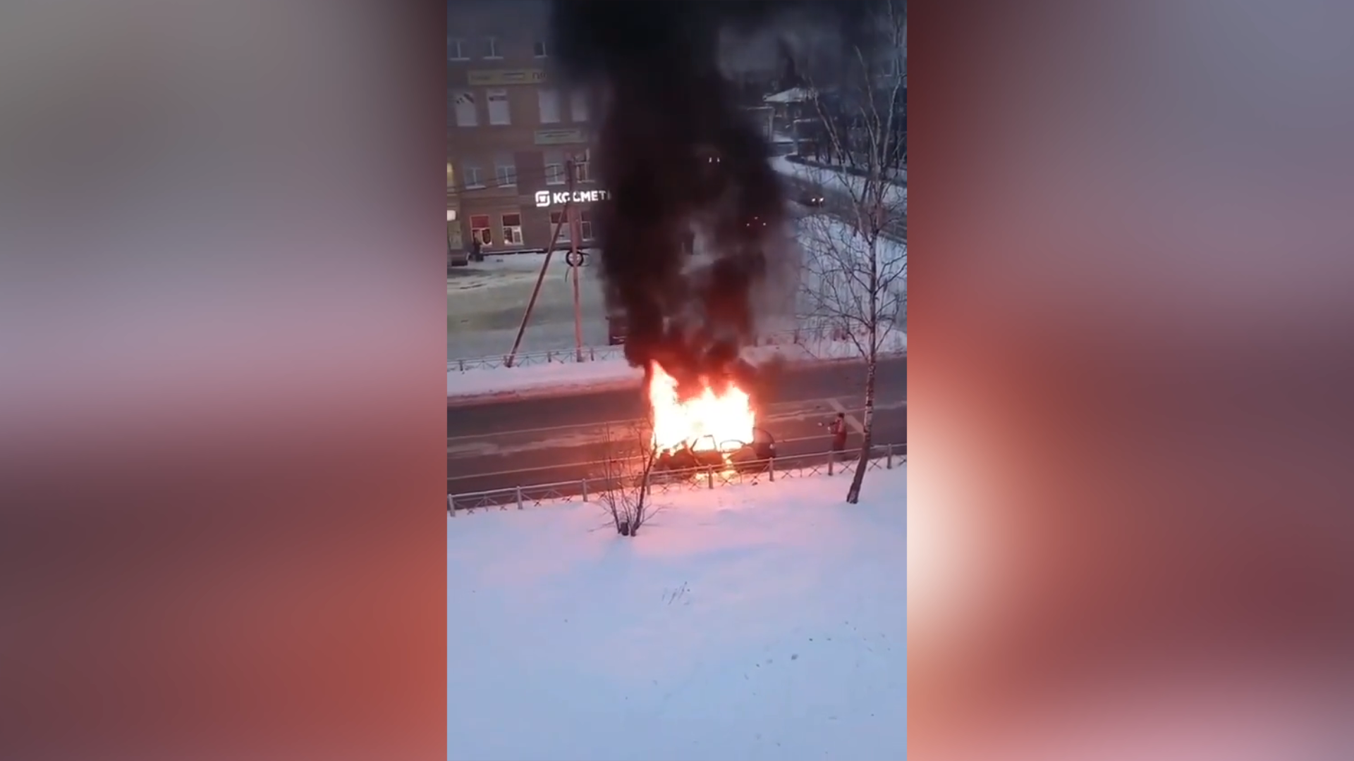 A wide frame from the video showing the burning vehicle on the street before the explosions.