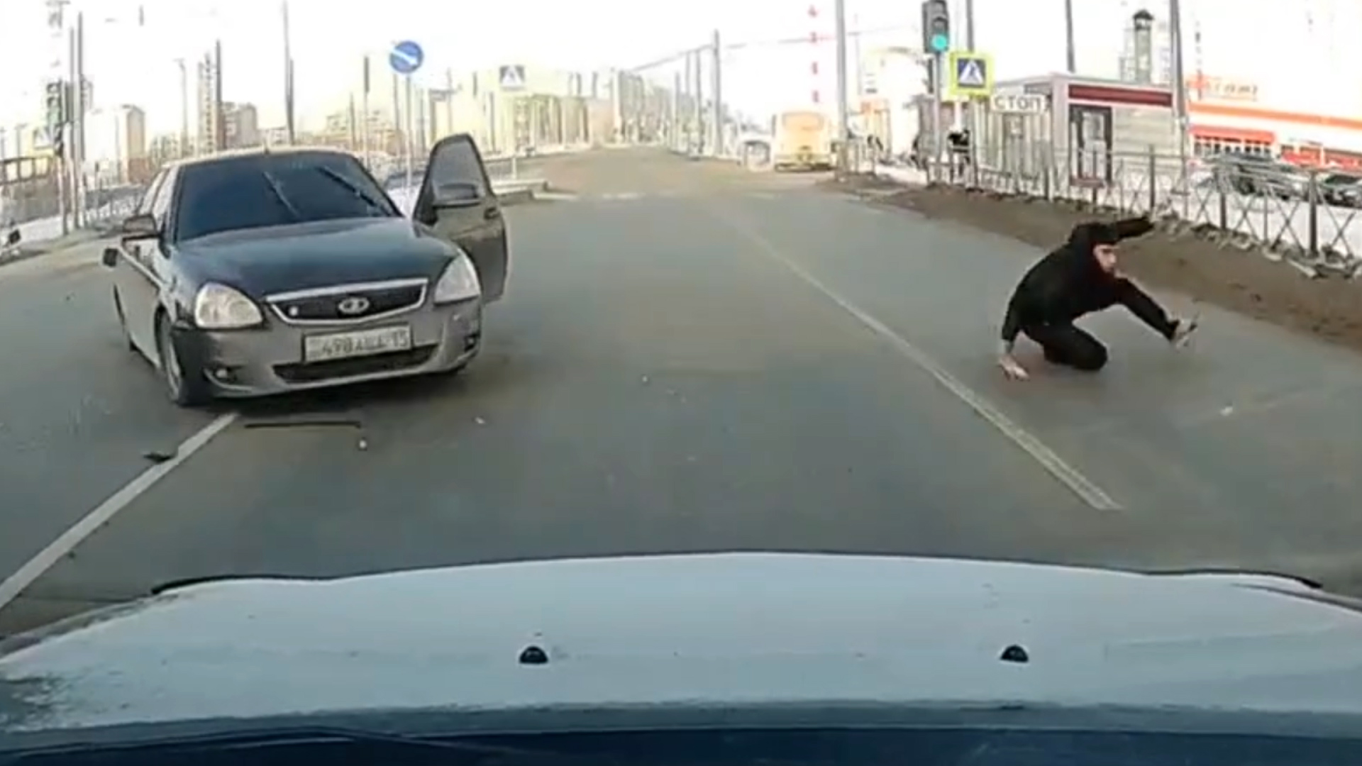 Dashcam frame showing a crashed car with its driver ejected onto the roadway at an intersection in Omsk, Russia.