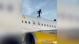 Man sitting on the roof of an Airbus A320 aircraft at Valencia Airport while the plane is on the tarmac.